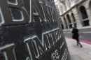 A pedestrian walks past a Bank sign in the City of London