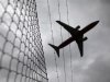 Passenger plane flies over a barbed wire fence