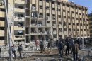 Syrian security personnel and civilians gather at the site where two explosions rocked the University of Aleppo in Syria's second largest city