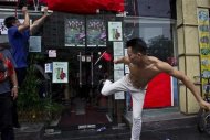 A man kicks the door of a Japanese pub decorated with Chinese national flags during a protest on the 81st anniversary of Japan's invasion of China, in Shenzhen, September 18, 2012. REUTERS/Keita Van