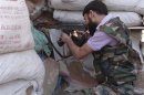 A Free Syrian Army fighter aims his weapon behind sandbags in the eastern al-Ghouta, near Damascus