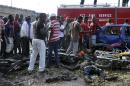 People gather at the site of a blast at the Nyanya Motor Park, about 16 kilometers (10 miles) from the center of Abuja, Nigeria, Monday, April 14, 2014. An explosion blasted through a busy commuter bus station on the outskirts of Abuja before 7 a.m. (0600 GMT) Monday as hundreds of people were traveling to work. (AP Photo/Gbemiga Olamikan)