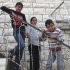 In this March 12, 2012 photograph, Mahmoud al-Alami, 10, left, stands in front of his home with his cousin Farah, center, and brother Mamoun in Beit Umar, West Bank. When Mahmoud was 9-years-old, an Israeli soldier caught him throwing rocks, took him out of his uncle's arms, slung him over his shoulders and took him away. Mahmoud says he was subsequently blindfolded and shackled, slapped and ordered to confess to throwing rocks at Israeli soldiers and identify other children doing the same. (AP Photo/Diaa Hadid)