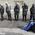 A protester wearing a Greek flag sits in front of riot police during a rally outside the Greek Parliament in Athens, Saturday, Feb. 11, 2012. The leaders of the two parties backing Greece's coalition government called on their deputies Saturday to back legislation that calls for harsh new austerity measures - essential if Greece is to get a new bailout deal worth euro 130 billion ($171.6 billion) and stave off bankruptcy. (AP Photo/Thanassis Stavrakis)
