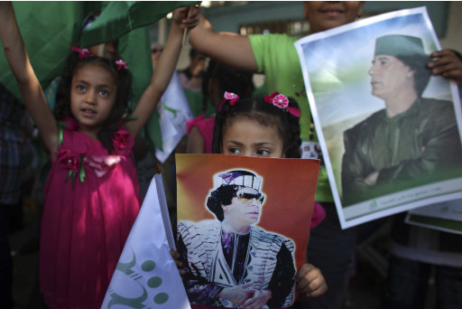 In this photo taken on a government-organized tour, a girl holds a poster of Libyan leader Moammar Gadhafi during a demonstration against NATO at a U.N. building in Tripoli, Libya, Saturday, July 2, 2011. The United States and Spain said Saturday they won't let Moammar Gadhafi's threats of retaliatory attacks in Europe deter their mission to protect Libyan civilians and force him to leave power after four decades of often unpredictable and sometimes violent rule. (AP Photo/Tara Todras-Whitehill)