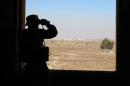 A rebel fighter looks through binoculars in Quneitra countryside