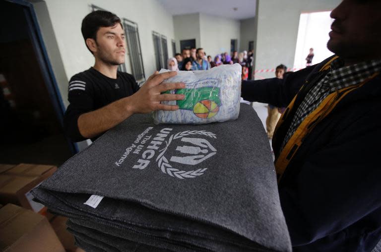 Syrian refugees receive thermal blankets and other humanitarian aid distributed by the United Nations High Commission for Refugees in the Lebanese town of Saadnayel in the Bekaa valley on November 15, 2013