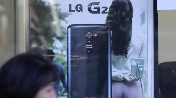A woman walks by an advertisement of LG Electronics' smartphone G2 in Seoul, South Korea, Wednesday, Oct. 16, 2013. The G2 and the G Pad 8.3, the flagship smartphone and tablet from LG Electronics Inc., are great mobile devices that have fantastic screens, top-end cameras and ample processing power. But making solid devices is not enough to stand apart from the crowd in the ultra-competitive mobile phone market, which probably pushed LG to make some bold design decisions in a bid to differentiate its G series from Samsung’s Galaxy line and Apple’s iPad mini. (AP Photo/Lee Jin-man)