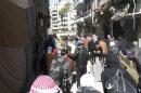 Civilians carry their belongings as they wait to be evacuated from a besieged area of Homs