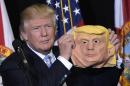 Republican presidential nominee Donald Trump holds a mask of himself wduring a campaign rally in Sarasota, Florida, on November 7, 2016