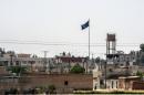 In a picture taken from Alcakale, Turkey, a flag of the Islamic State flutters amongst buildings in the center of the Syrian city Tal Abyad on June 13, 2015