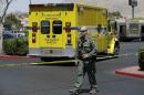 A Las Vegas Metropolitan Police officer walks near the scene of a shooting, Sunday, June 8, 2014 in Las Vegas. Police say two suspects shot two officers at a Las Vegas pizza parlor before fatally shooting a person and turning the guns on themselves at a nearby Walmart. (AP Photo/John Locher)