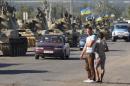 Local residents watch as a column of Ukrainian tanks travel in the Donetsk region on September 3, 2014