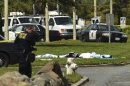 Bodies lie covered on the grass as Oakland Police work near Oikos University in Oakland, Calif., Monday, April 2, 2012. A gunman opened fire at Oikos University in California Monday, killing at least five people, law enforcement sources close to the investigation said. Police say they have a suspect in custody. (AP Photo/Noah Berger)