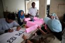 Election workers prepare voting booths for election to vote for governor, at Muara Baru flat in Jakarta