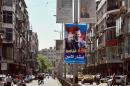 Syrians walk on a street decorated with campaign posters of the June 3 presidential election in Damascus, Syria, Monday, May 12, 2014. The Arabic, top center, reads, "Let's fight corruption, Hassan al-Nouri, June 4, 2014." The one, center, reads, "Damascus spreads flowers for the loyal Bashar." On billboards and in posters taped to car windows, new portraits of President Bashar Assad filled the streets of Damascus on Sunday as Syria officially opened its presidential campaign despite a crippling civil war that has devastated the country and left large chunks of territory outside of government control. Assad faces two other candidates in the race: Maher Hajjar and Hassan al-Nouri, both members of the so-called internal opposition tolerated by the government. (AP Photo)