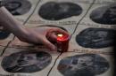 A woman places a lit candle on portraits of Armenian intellectuals who were deported under Ottoman rule during the World War I, on April 24, 2014 in Istanbul