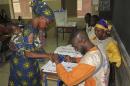 A woman carries a baby on her back as she casts her vote during a legislative vote at a polling station in Lafiabougou, Bamako