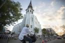 A bicyclist rides in front of the Emanuel AME Church, Sunday, June 21, 2015, before the first worship service since nine people were fatally shot at the church during a Bible study group, in Charleston, S.C. (AP Photo/Stephen B. Morton)