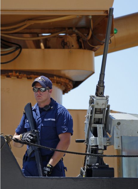 An armed crew member from the U.S.Coast Guard Cutter Oak keeps a watchful eye as they unload 15,000 pounds of cocaine worth more than $180 million at Base Support Unit Miami