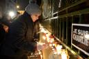 People light candles as they pay tribute to victims of the attack against the French satirical weekly Charlie Hebdo, in front of the French embassy in Budapest, Hungary, Thursday, Jan. 8, 2015, a day after 12 people were slain by two armed men who stormed the Paris offices of the magazine. Inscriptions read "I am Charlie". (AP Photo/MTI, Lajos Soos)