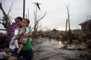A woman carries her child through rubble from destroyed homes and uprooted trees in the town of Palo on November 23, 2013