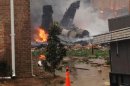 The burning fuselage of an F/A-18 Hornet lies smoldering after crashing into a residential building in Virginia Beach, Va., Friday, April 6, 2012. The Navy did not immediately return telephone messages left by The Associated Press, but media reports indicate the two aviators were able to eject from the jet before it crashed. They were being treated for injuries that were not considered life threatening. (AP Photo/Zack Zapatero) MANDATORY CREDIT