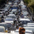 A woman passes a street as motorcyclists make their way through long lines of vehicles in central Athens on Monday, Sept. 26, 2011.  The Greek capital faced extensive traffic jams due to a 24-hour Metro, tram and suburban strikes, while buses and trolleys were to stop operating for several hours in the middle of the day.(AP Photo/Petros Giannakouris)
