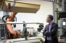 Coffin maker Jagdt (CEO of lignotech Massivholz GmbH) watches a robot arm moving a coffin in Berlin