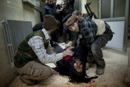 In this Sunday, March 11, 2012 photo, Syrian rebels carry the dead body of a comrade to a morgue after heavy fighting with Syrian government forces in Idlib, north Syria. Syrian activists said Monday that pro-government gunmen have killed several people including children in a rebel stronghold recaptured by the government in the embattled central city of Homs. (AP Photo/Rodrigo Abd)