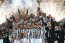 Juventus players hold up the Italian Cup trophy as they celebrate at the end of a Serie A soccer match between Juventus and Napoli at the Juventus stadium, in Turin, Italy, Saturday, May 23, 2015. Juventus beat Napoli 3-1 in Serie A on Saturday as it celebrated winning the double of the Italian league and cup in a party atmosphere in Turin. (AP Photo/Massimo Pinca)