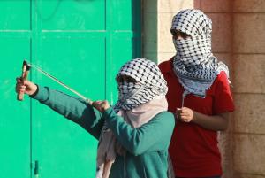 A Palestinian female protester uses a slingshot to …