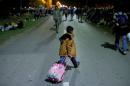 A migrant child crosses the street with a luggage in Tovarnik