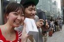 Kae Shibata 20, left, and Yutaro Noji, 21, show off Apple's iPhone 5 after they bought at a store in Tokyo Friday morning, Sept. 21, 2012. (AP Photo/Koji Sasahara)