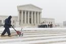 A workman clears snow from the plaza at the U.S. Supreme Court in Washington in Washington, Monday, March 3, 2014, as visitors line up to hear arguments. The National Weather Service has issued a Winter Storm Warning for the greater Washington Metropolitan region, prompting area schools and the federal government to close for the wintry weather. (AP Photo/J. Scott Applewhite)