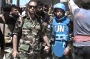 This image made from amateur video released by the Shaam News Network and accessed Sunday, April 22, 2012, purports to show a Free Syrian Army solider accompanying a UN observer in Rastan town in Homs, Syria. U.N. cease-fire monitors toured a rebel-held town in central Syria Sunday with army defectors, while government troops pounded a Damascus suburb with artillery and heavy machine guns, activists said. (AP Photo/Shaam News Network via AP video) TV OUT, THE ASSOCIATED PRESS CANNOT INDEPENDENTLY VERIFY THE CONTENT, DATE, LOCATION OR AUTHENTICITY OF THIS MATERIAL