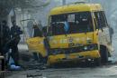 Investigators inspect a damaged bus at the site of a suicide attack in Kabul, on January 26, 2014