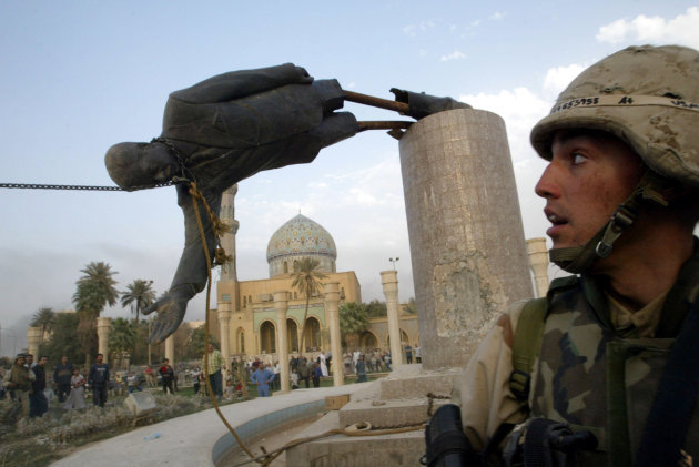 A U.S. soldier watches as a statue of Iraq's President Saddam Hussein falls in central Baghdad April 9, 2003. U.S. troops pulled down a 20-foot (six metre) high statue of President Saddam Hussein in central Baghdad on Wednesday and Iraqis danced on it in contempt for the man who ruled them with an iron grip for 24 years. [In scenes reminiscent of the fall of the Berlin Wall in 1989, Iraqis earlier took a sledgehammer to the marble plinth under the statue of Saddam. Youths had placed a noose around the statue's neck and attached the rope to a U.S. armoured recovery vehicle.]