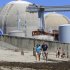 FILE - This file photo taken June 30, 2011 shows beach-goers walking on the sand near the San Onofre nuclear power plant in San Clemente , Calif. The twin reactors at the plant have been idled while investigators determine why tubing carrying radioactive water is eroding at an unusual rate, and the Nuclear Regulatory Commission chairman will visit the plant Friday, April 6, 2012, to highlight the agency's concern over the ailing equipment. (AP Photo, Lenny Ignelzi, File)