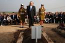 Israel's Prime Minister Benjamin Netanyahu pays his respects in front of the grave of former Prime Minister Ariel Sharon during his funeral on January 13, 2014 at the family ranch Havat Shikmin