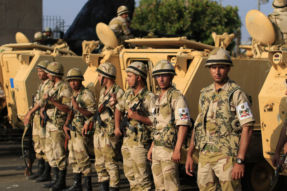 Egyptian army soldiers take their positions near armored vehicles to guard the entrances of Tahrir square, in Cairo, Egypt, Monday, July 8, 2013. Egyptian military officials said gunmen killed at least five supporters of the former president when people tried to storm a military building in Cairo. The official, who declined to be named because he was not authorized to brief reporters, also said a group had tried to storm the headquarters of the Republican Guard. He added that those killed had been supporters of former President Mohammed Morsi camped outside the building in protest at his overthrow. (AP Photo/Hassan Ammar)