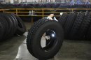 An employee inspects the interior of a newly-made tyre with a flashlight at a tyre factory in Hangzhou