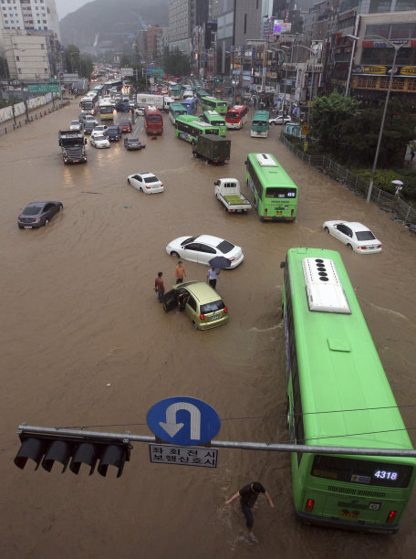 People drive vehicles through a flooded road in Seoul, South Korea, Wednesday, July 27, 2011. Heavy rain sent a landslide barreling into a resort in Chuncheon, a northern South Korean town Wednesday. (AP Photo/Lim Hun-jung) KOREA OUT