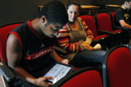 In this Aug. 23, 2011 photo, sophomore Lenny Thelusma, 16, checks out his new iPad as his mother, Tara Killion, looks on at Burlington High School in Burlington, Mass. Burlington is giving iPads this year to every one of its 1,000-plus high school students. Some classes will still have textbooks, but the majority of work and lessons will be on the iPads. (AP Photo/Elise Amendola)