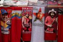 Iconic T-shirts styled with images of Venezuela's President Hugo Chavez are displayed for sale next to a T-shirt of Venezuelan musician Ali Primera, in Caracas, Venezuela, Friday, Dec. 28, 2012. The obsessive, circular conversations about Chavez's health dominate family dinners, plaza chit-chats and social media sites in this country on edge since its larger-than-life leader went to Cuba for emergency cancer surgery more than two weeks ago. The man whose booming voice once dominated the airwaves for hours at a time has not been seen or heard from since.(AP Photo/Fernando Llano)