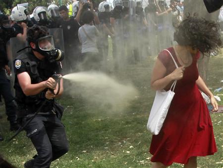 A Turkish riot policeman uses tear gas against a woman as people protest against the destruction of trees in a park brought about by a pedestrian project, in Taksim Square in central Istanbul May 28, 2013.REUTERS/Osman Orsal