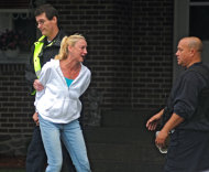 In this Saturday, July 28, 2012 photo, Kelleen Benway is detained by a police officer after she returned to her home on Main Street in Oxford, Mass. where multiple shootings occurred. Daryl Benway, 41, who had recently separated from Kelleen, shot his two children, killing his 7-year-old daughter, before committing suicide, prosecutors said. Kelleen was later released. (AP Photo/Worcester Telegram & Gazette, Steve Lanava)
