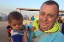 This handout image received from Britain's Foreign and Commonwealth Office on September 15, 2014 shows British aid worker, Alan Henning holding a child in a refugee camp on the Turkish-Syrian border