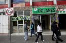People walk past a foreign exchange building and a money transfer business house in Ixmiquilpan