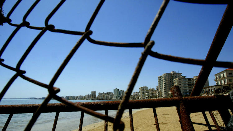 FILE - In this Monday, May 5, 2003 file photo deserted hotels in an area used by the Turkish military are seen through a wire fence in the Turkish-occupied area in the abandoned coastal city of Varosha, in southeast of the island of Cyprus. Time virtually stopped in 1974 for the Mediterranean tourist playground of Varosha. When Turkey invaded Cyprus in the wake of a coup by supporters of union with Greece, thousands of residents fled, and chain-link fences enclosed a glamorous resort that it’s said once played host to Hollywood royalty like Elizabeth Taylor. (AP Photo/Petros Karadjias, file)